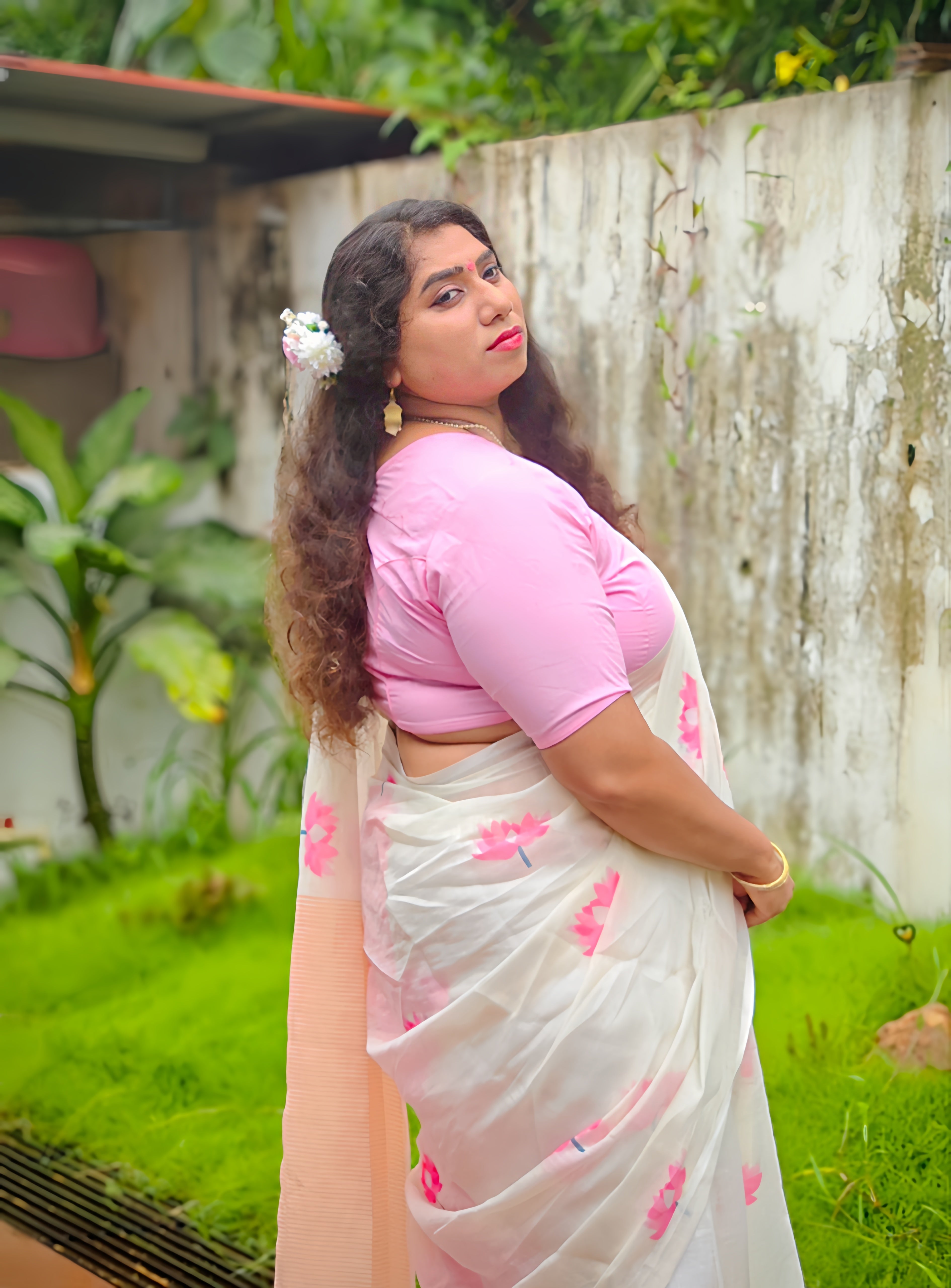Woman wearing a soft cotton linen white saree with pink lotus floral print and matching pink blouse by Vyra Fashion. Perfect for festive, office and casual wear.